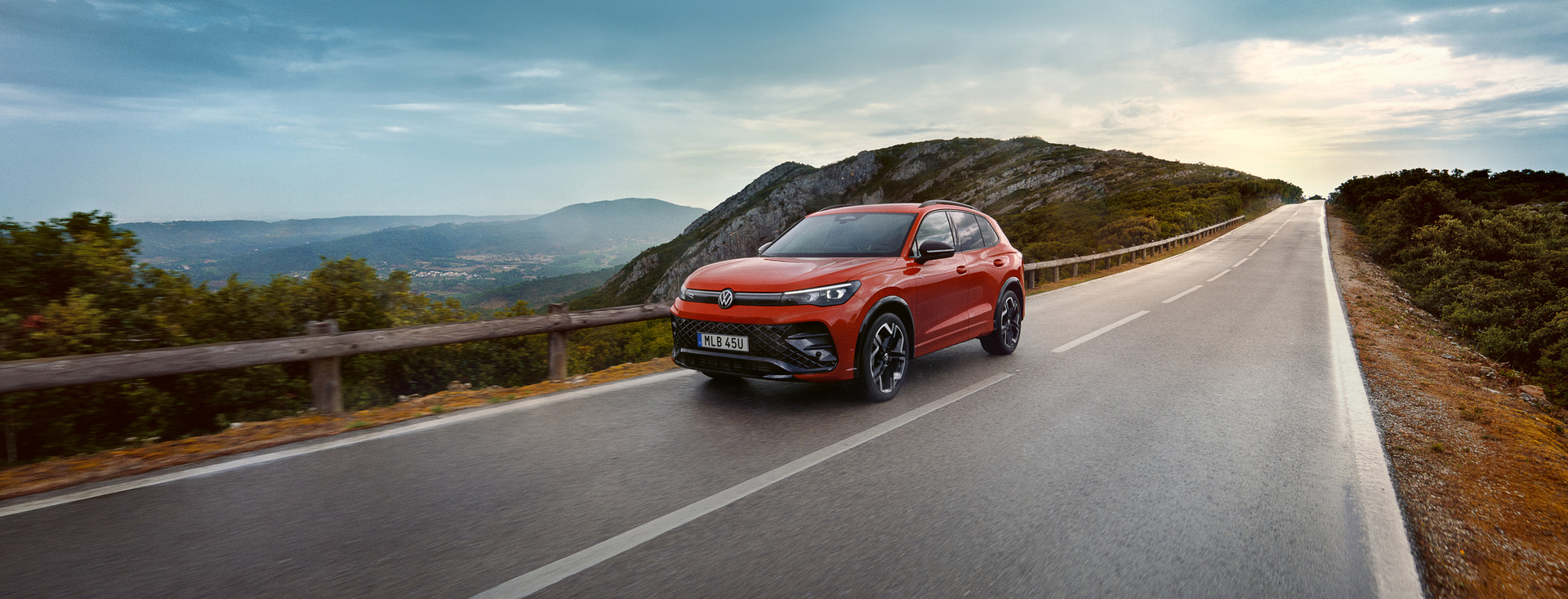 En röd VW Tiguan kommer i hög fart på landsväg med berg i bakgrunden