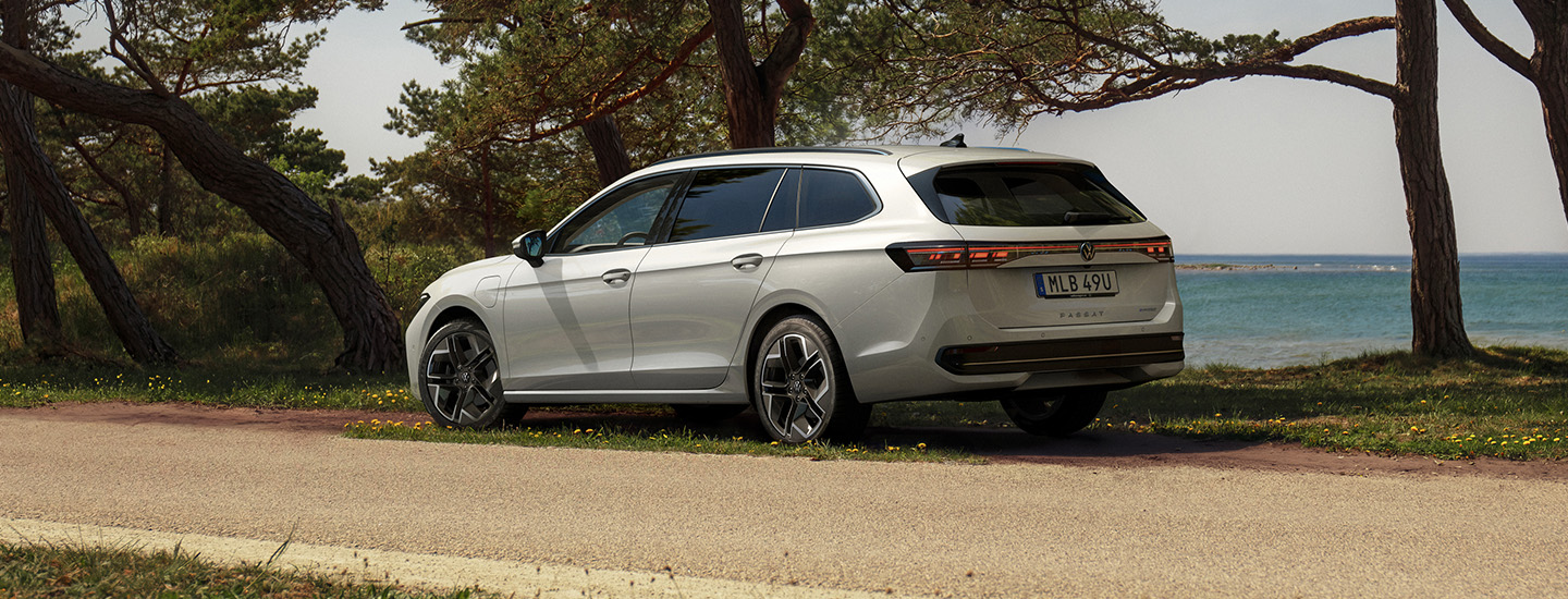 Nya Volkswagen Passat, ljus silvermetallic lack. Parkerad längs en väg med hav och tallar i bakgrunden