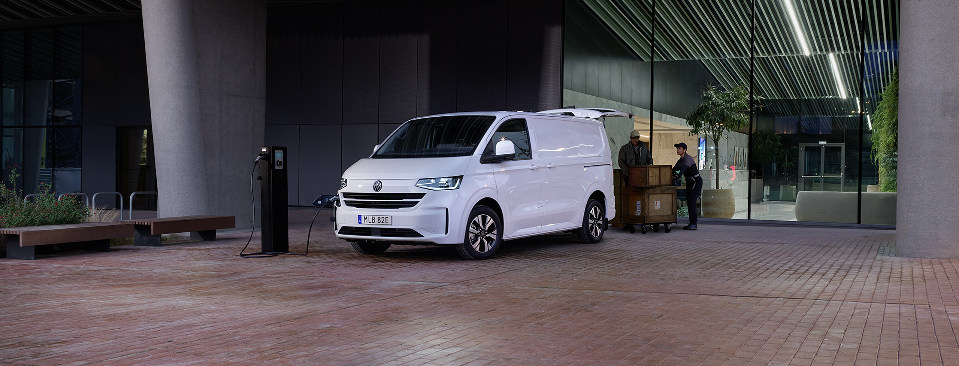 En vit Transporter som lastas med lådor av två personer