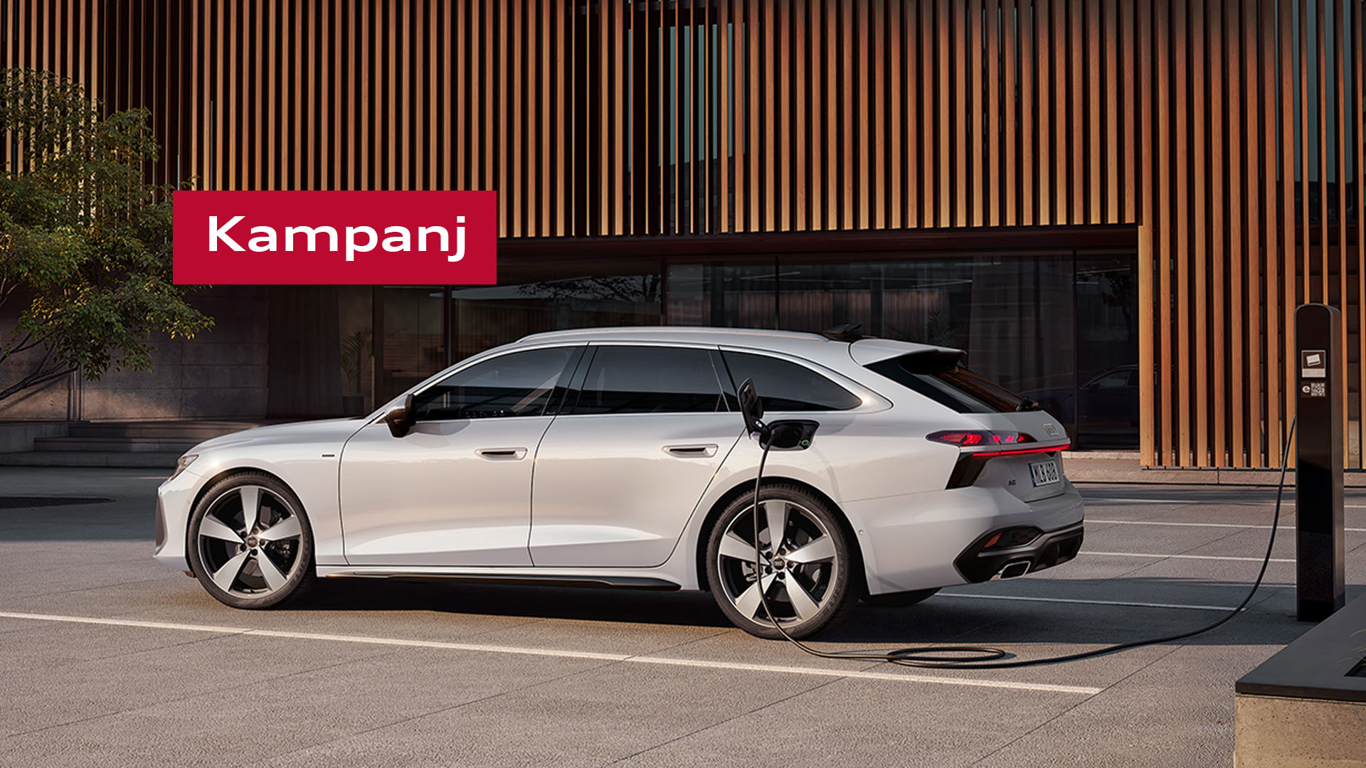 Audi A6 Avant e-hybrid quattro i silvergrå metallic står parkerad med laddsladden i