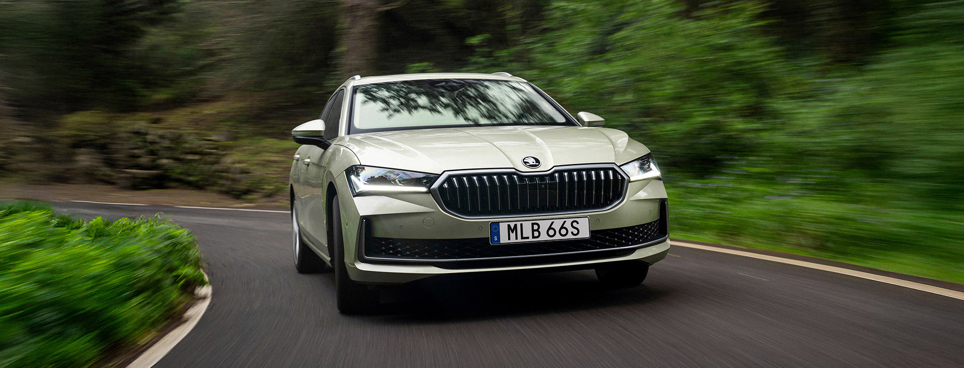 Skoda Superb iV 130 Edition, kör på landsväg i skogslandskap